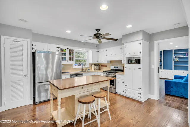 a kitchen with kitchen island a stove a refrigerator and a dining table with wooden floor