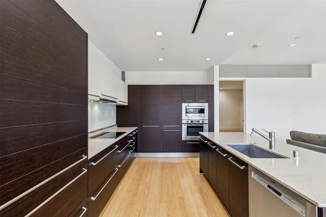 a living room with stainless steel appliances kitchen island granite countertop a refrigerator and a sink