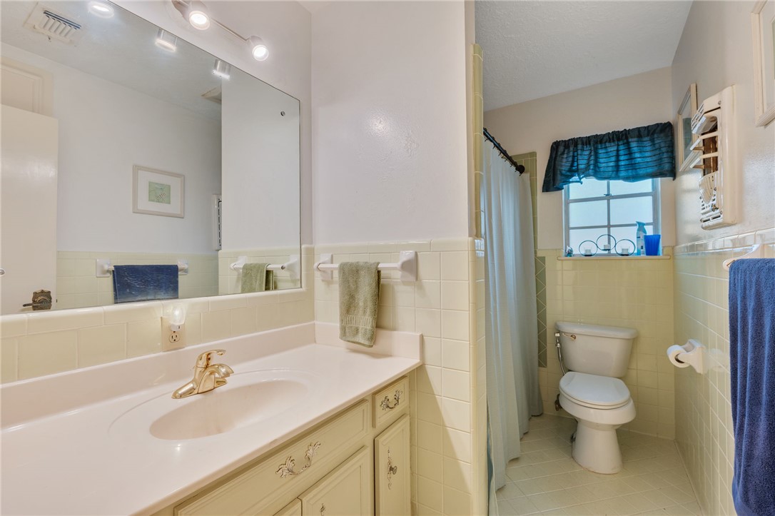 503 Calvert Street Hearne, TX 77859 - Photo 11 of 30 Bathroom with vanity, light tile patterned floors, tile walls, wainscoting, and curtained shower