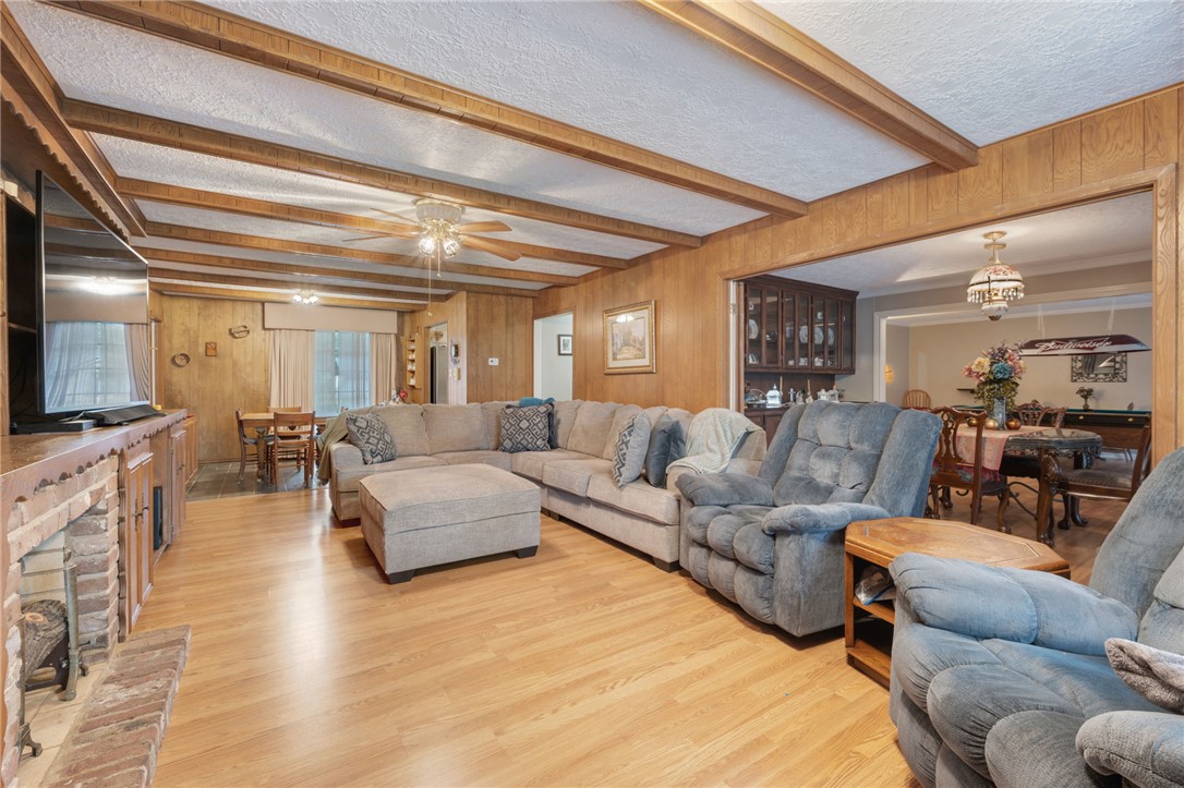 503 Calvert Street Hearne, TX 77859 - Photo 17 of 30 Living room featuring beam ceiling, a textured ceiling, light wood-style flooring, wooden walls, and a chandelier