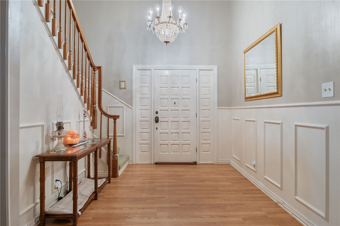 503 Calvert Street Hearne, TX 77859 - Photo 2 of 30 Entryway featuring a chandelier, a decorative wall, wood finished floors, stairs, and a wainscoted wall