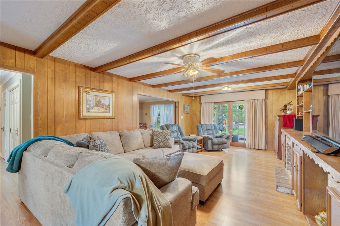 503 Calvert Street Hearne, TX 77859 - Photo 21 of 30 Living area with beam ceiling, wood walls, light wood-type flooring, a textured ceiling, and a ceiling fan