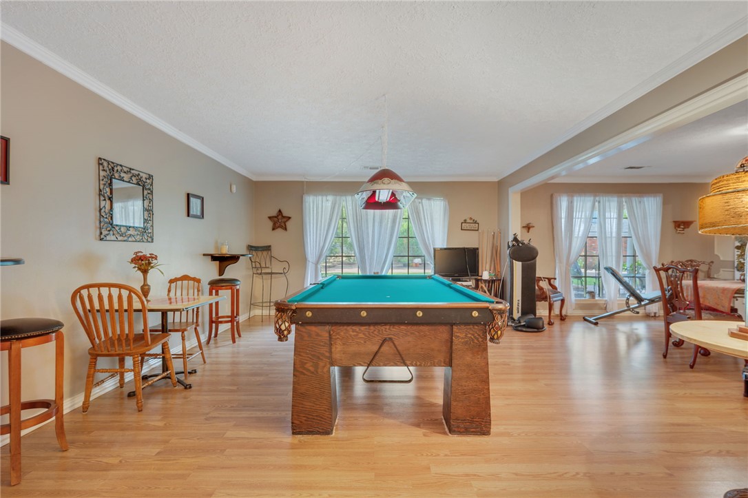503 Calvert Street Hearne, TX 77859 - Photo 4 of 30 Recreation room with ornamental molding, light wood-style flooring, healthy amount of natural light, billiards, and a textured ceiling