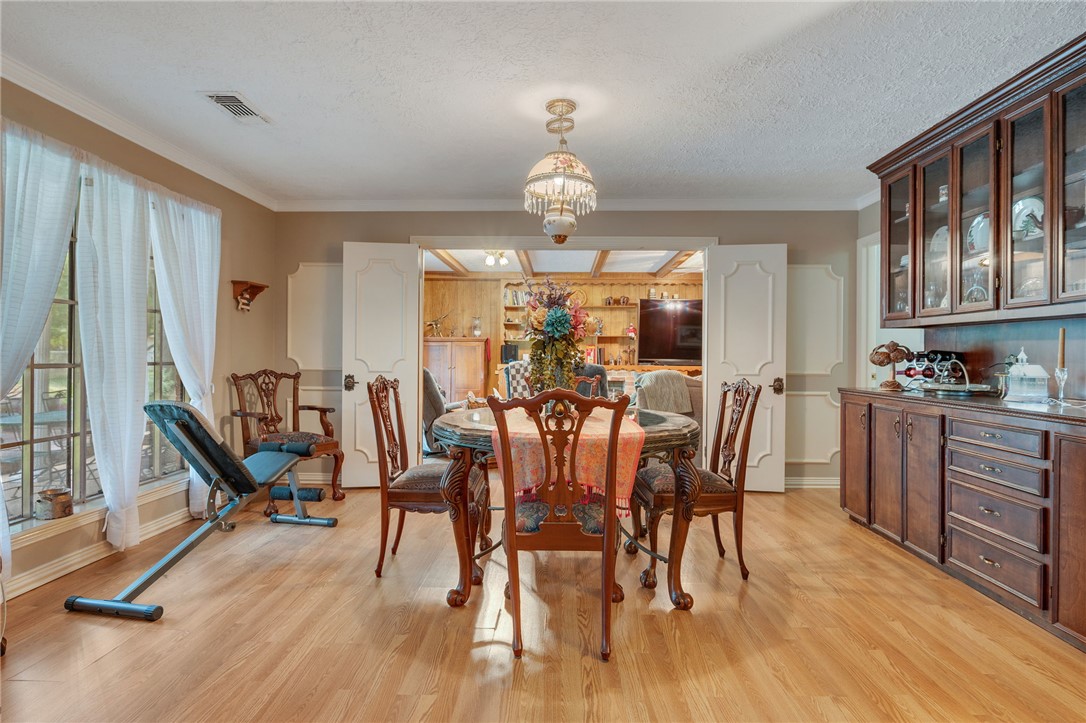 503 Calvert Street Hearne, TX 77859 - Photo 5 of 30 Dining space featuring light wood finished floors, a chandelier, a textured ceiling, and ornamental molding