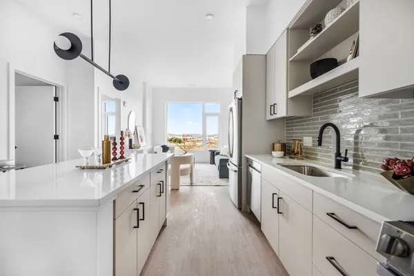 a kitchen with white cabinets appliances a sink and a counter top space