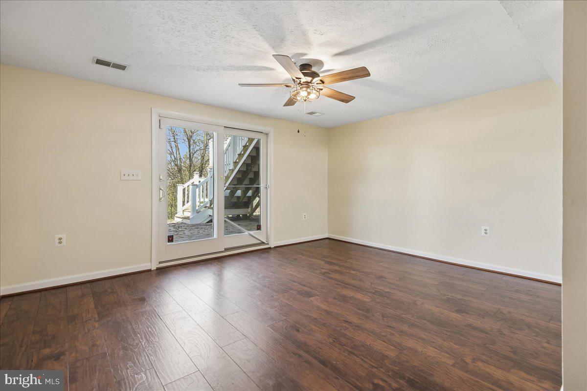 6413 White Peach Place Columbia, MD 21045 - Photo 15 of 31 an empty room with wooden floor chandelier fan and windows
