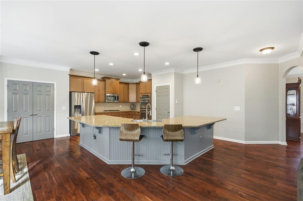 4965 Cheltenham Place Cumming, GA 30041 - Photo 5 of 47 a view of kitchen with stainless steel appliances kitchen island granite countertop a table chairs and a wooden floor