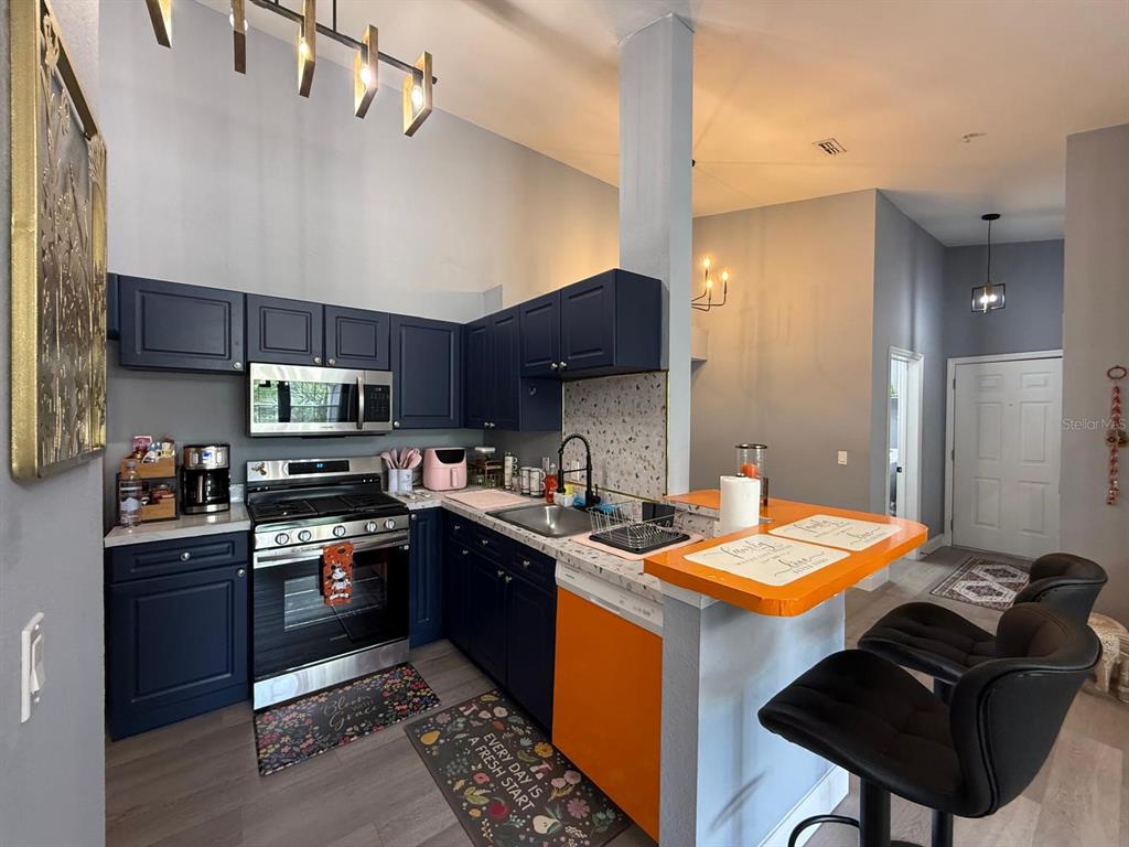 3391 South Kirkman Road, Unit 1236 Orlando, FL 32811 - Photo 4 of 30 a kitchen with stainless steel appliances kitchen island granite countertop a sink dishwasher stove and refrigerator with wooden cabinets