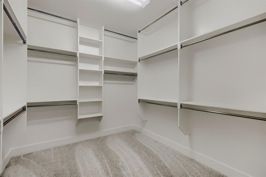4407 Windy Point Road Oak Point, TX 75068 - Photo 17 of 27 Custom closet system featuring white shelving units, multiple hanging rods, built-in vertical shelving, and recessed ceiling lighting