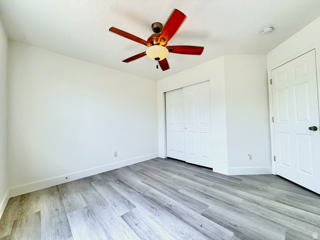 1705 80 East Tooele, UT 84074 - Photo 11 of 22 Room featuring wood-finish flooring, white baseboards, a ceiling fan with light fixture, and a paneled bifold closet door