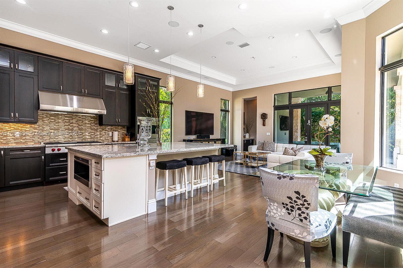 17766 Cadena Drive Boca Raton, FL 33496 - Photo 5 of 28 a kitchen with stainless steel appliances kitchen island granite countertop a stove a sink dishwasher a dining table and chairs with wooden floor