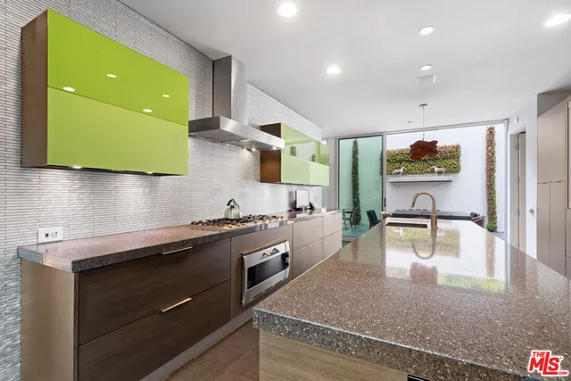 a large kitchen with kitchen island a large counter top stainless steel appliances a sink and living room view