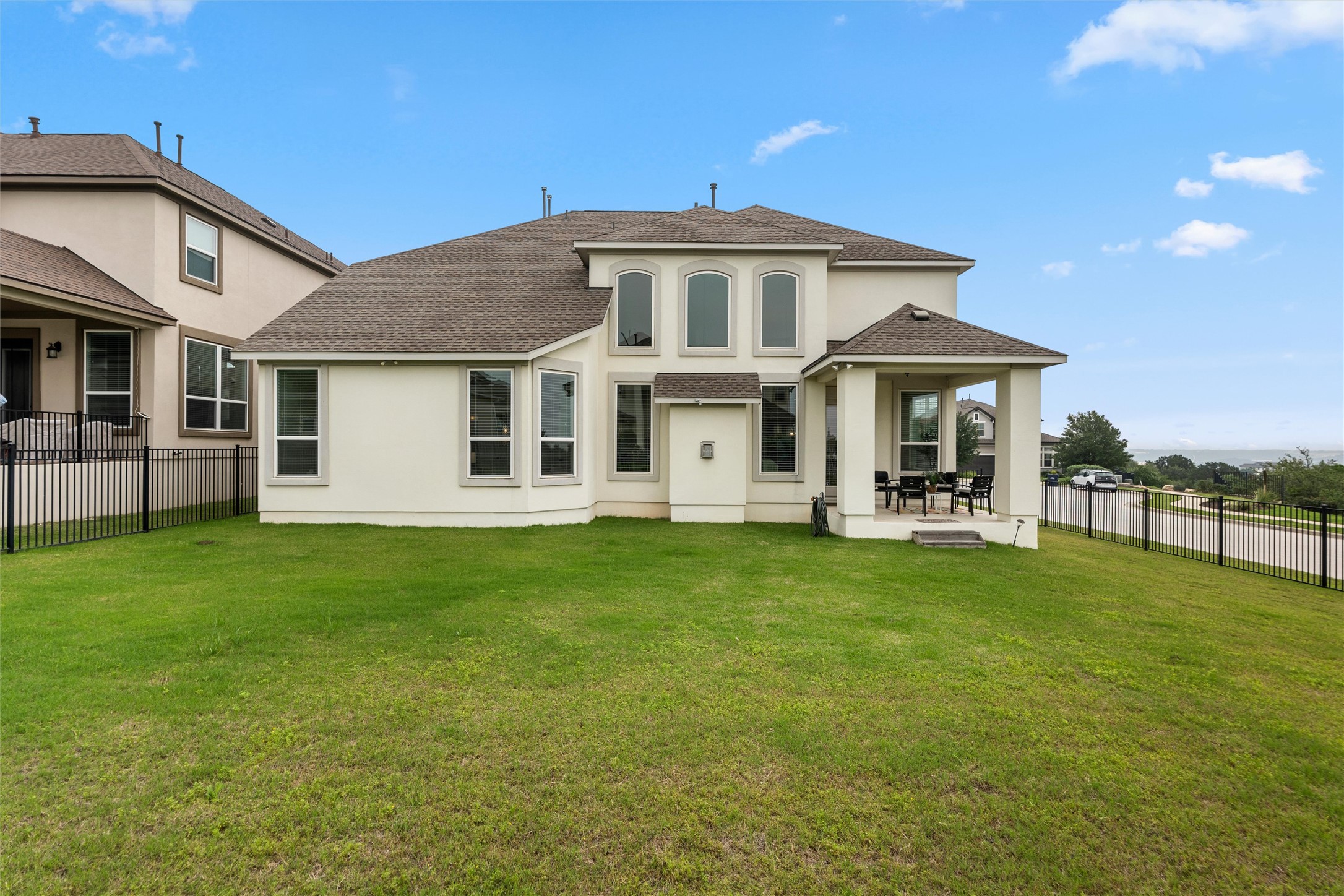 1733 Siena Sunset Road Leander, TX 78641 - Photo 11 of 40 Expansive backyard featuring a manicured lawn, a covered patio, wrought iron fencing, and multi-paned windows