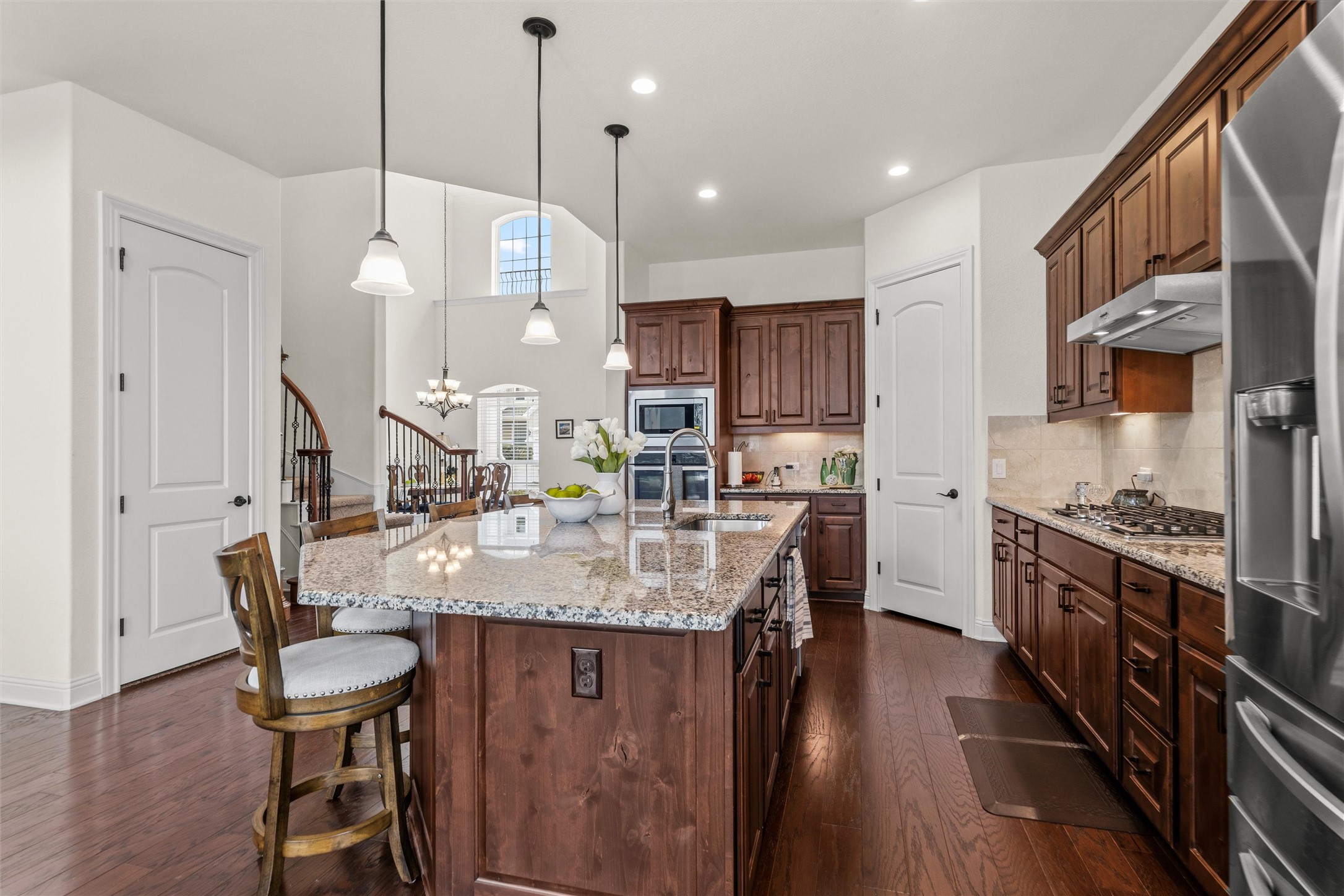 1733 Siena Sunset Road Leander, TX 78641 - Photo 17 of 40 Spacious kitchen featuring a large island with granite countertops, rich wood-finish cabinetry, stainless steel appliances, and wood-finish flooring
