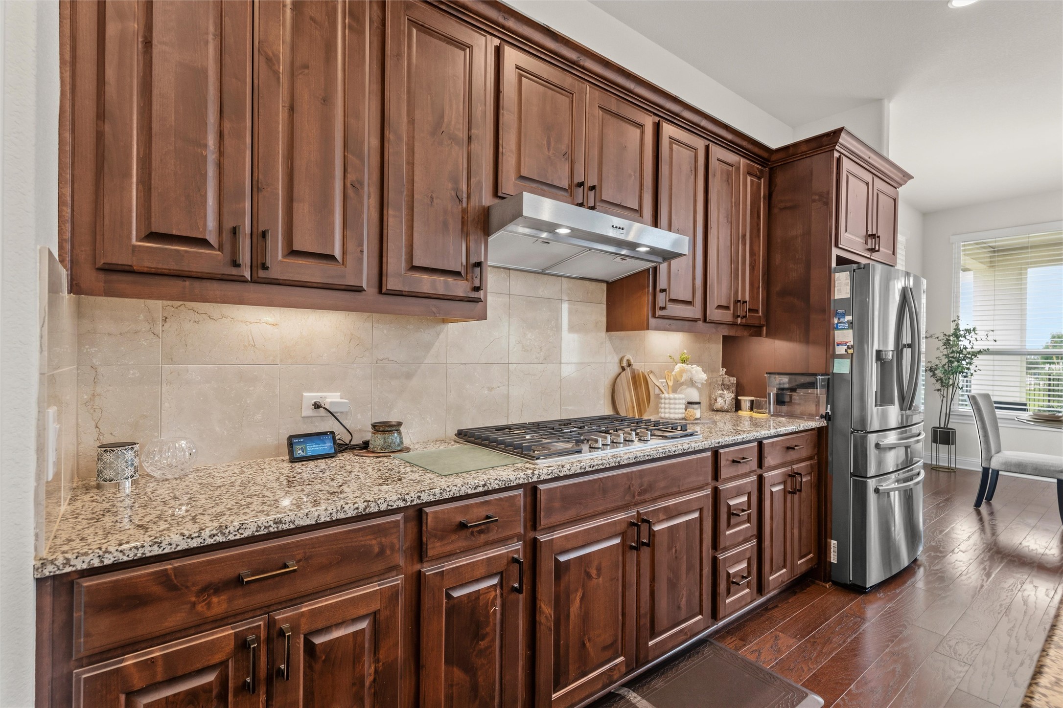1733 Siena Sunset Road Leander, TX 78641 - Photo 18 of 40 Kitchen featuring rich wood cabinetry, granite countertops, a tile backsplash, and stainless steel appliances