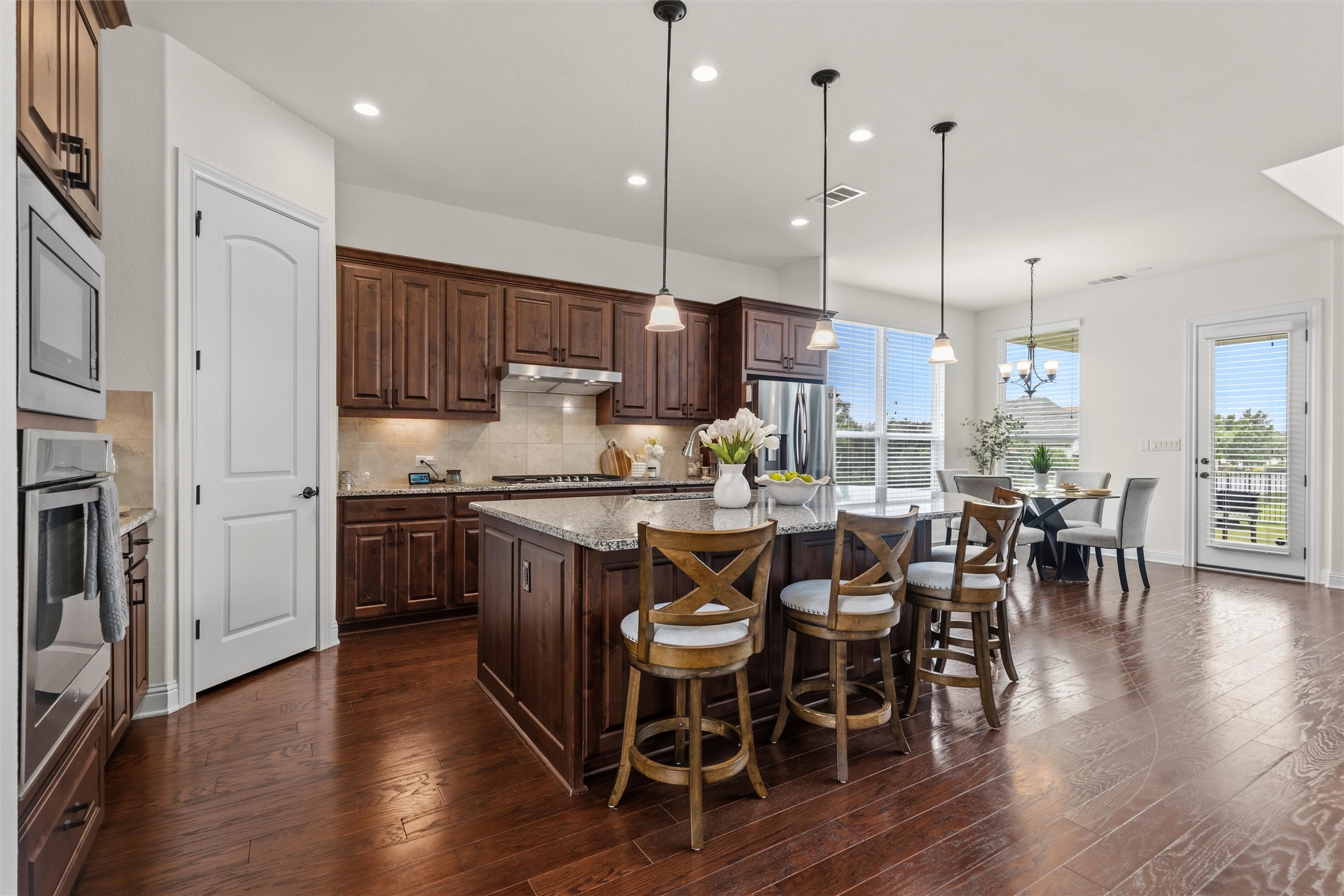 1733 Siena Sunset Road Leander, TX 78641 - Photo 20 of 40 Kitchen featuring a large island with stone countertop, dark wood-finish cabinetry, stainless steel appliances, and wood-finish flooring