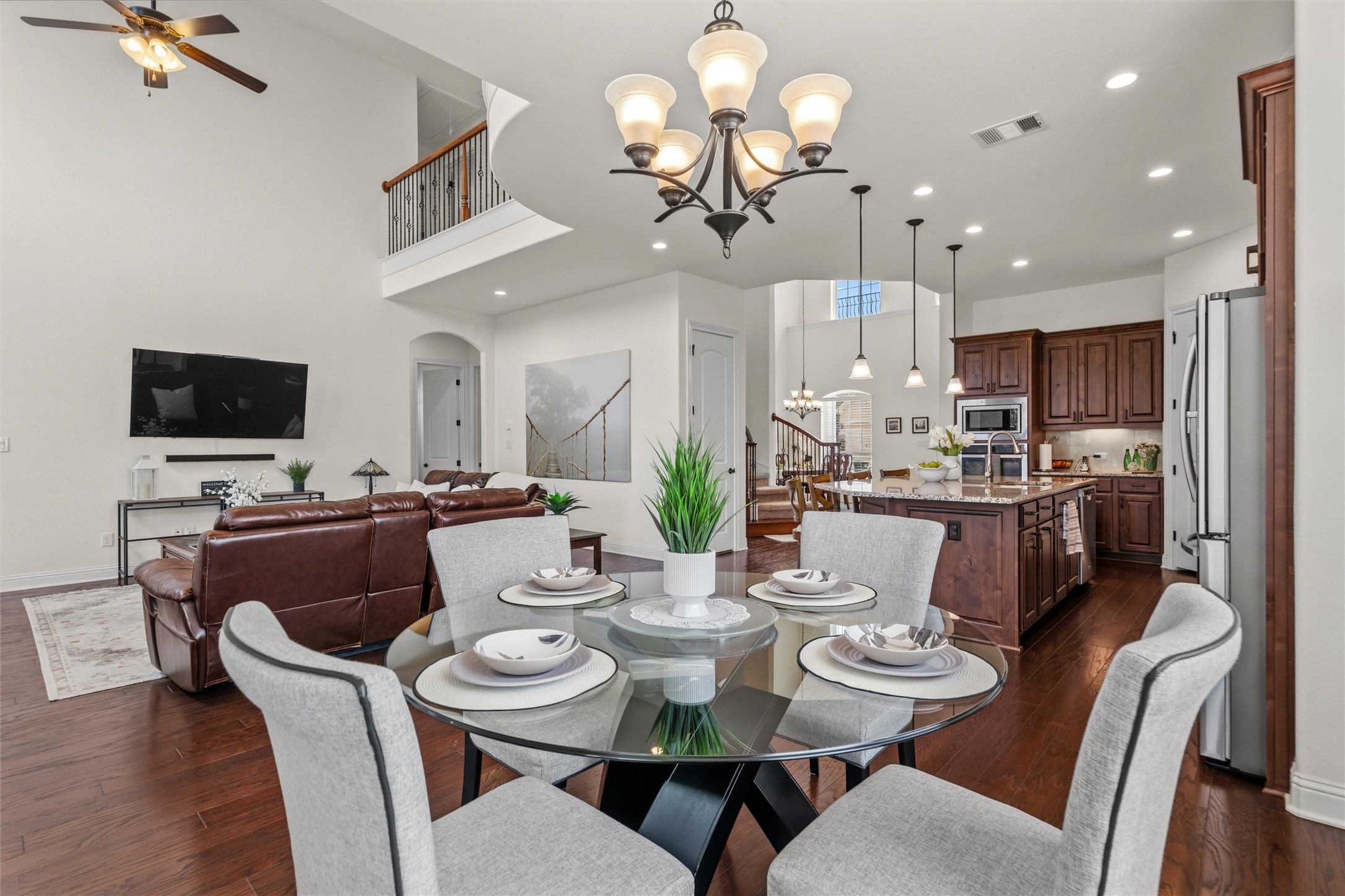 1733 Siena Sunset Road Leander, TX 78641 - Photo 22 of 40 Open-concept living space featuring wood-finish flooring, a two-story ceiling, and a prominent kitchen island with pendant lighting