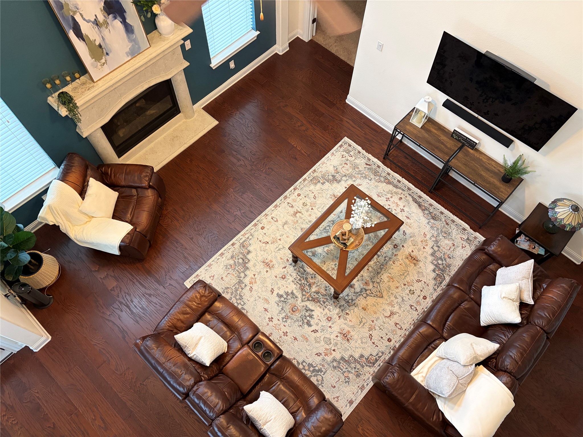 1733 Siena Sunset Road Leander, TX 78641 - Photo 26 of 40 Open-concept living area featuring wood-finish flooring, a decorative area rug, and a central fireplace with an ornate mantel