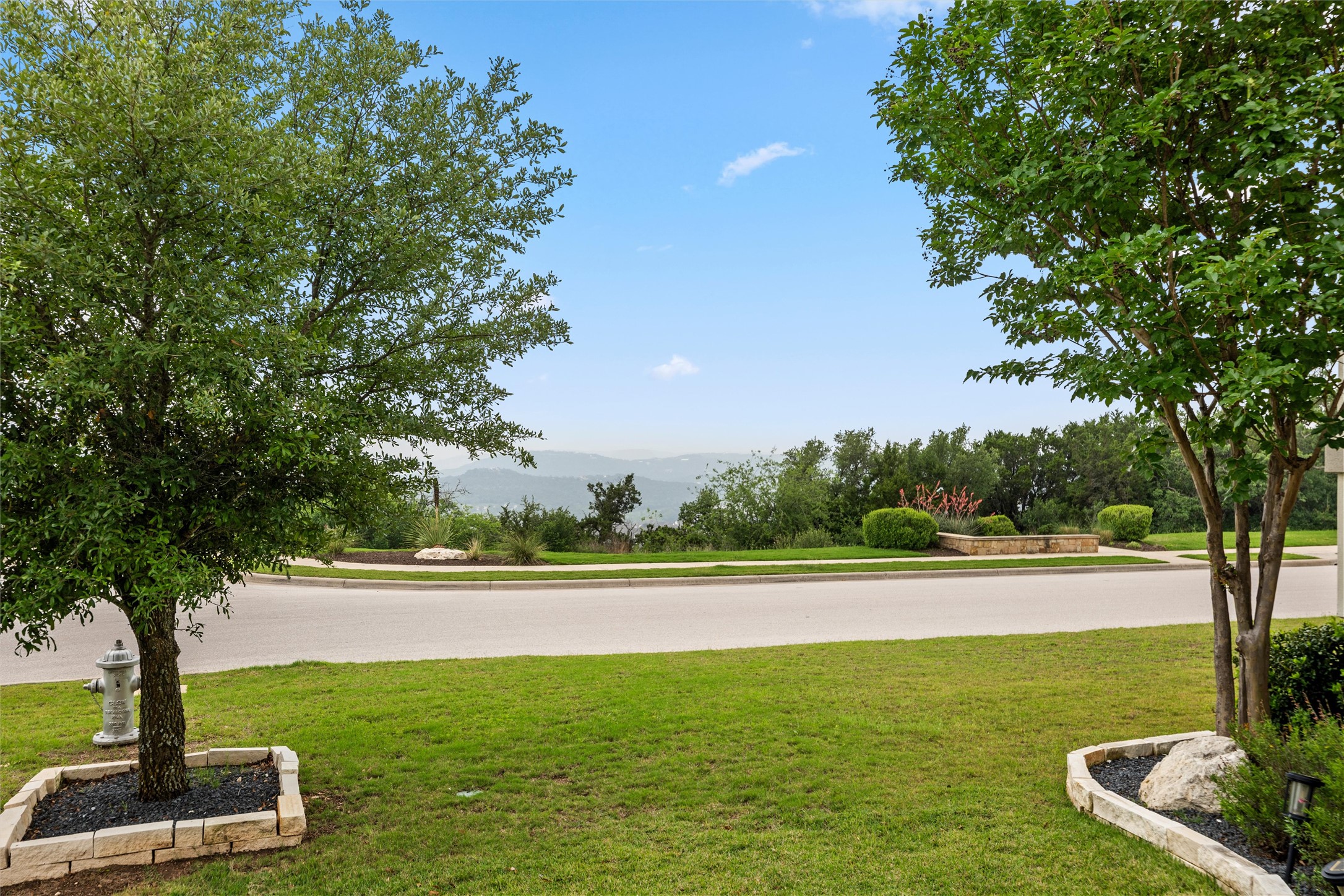1733 Siena Sunset Road Leander, TX 78641 - Photo 3 of 40 Expansive green lawn with mature trees and stone-edged landscaping