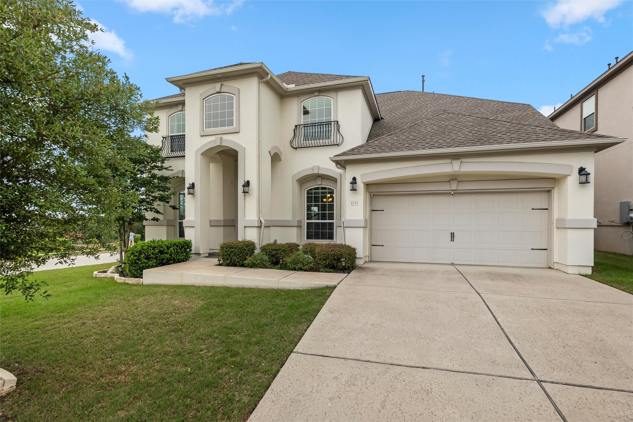 1733 Siena Sunset Road Leander, TX 78641 - Photo 40 of 40 Stucco exterior with arched entryways, a three-car garage, and second-story Juliet balconies with wrought iron railings