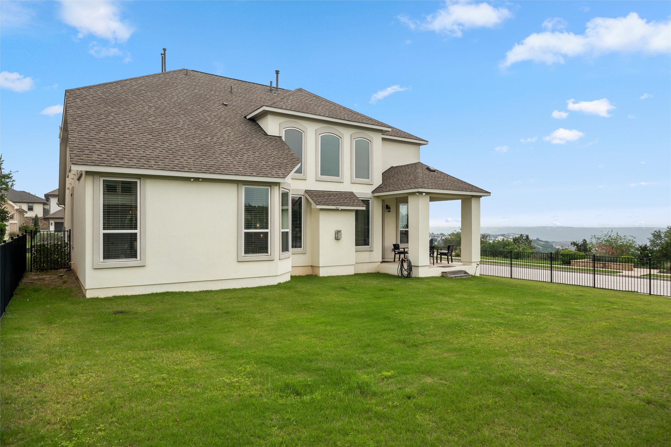 1733 Siena Sunset Road Leander, TX 78641 - Photo 10 of 40 Expansive green lawn bordering a two-story stucco exterior with a covered patio