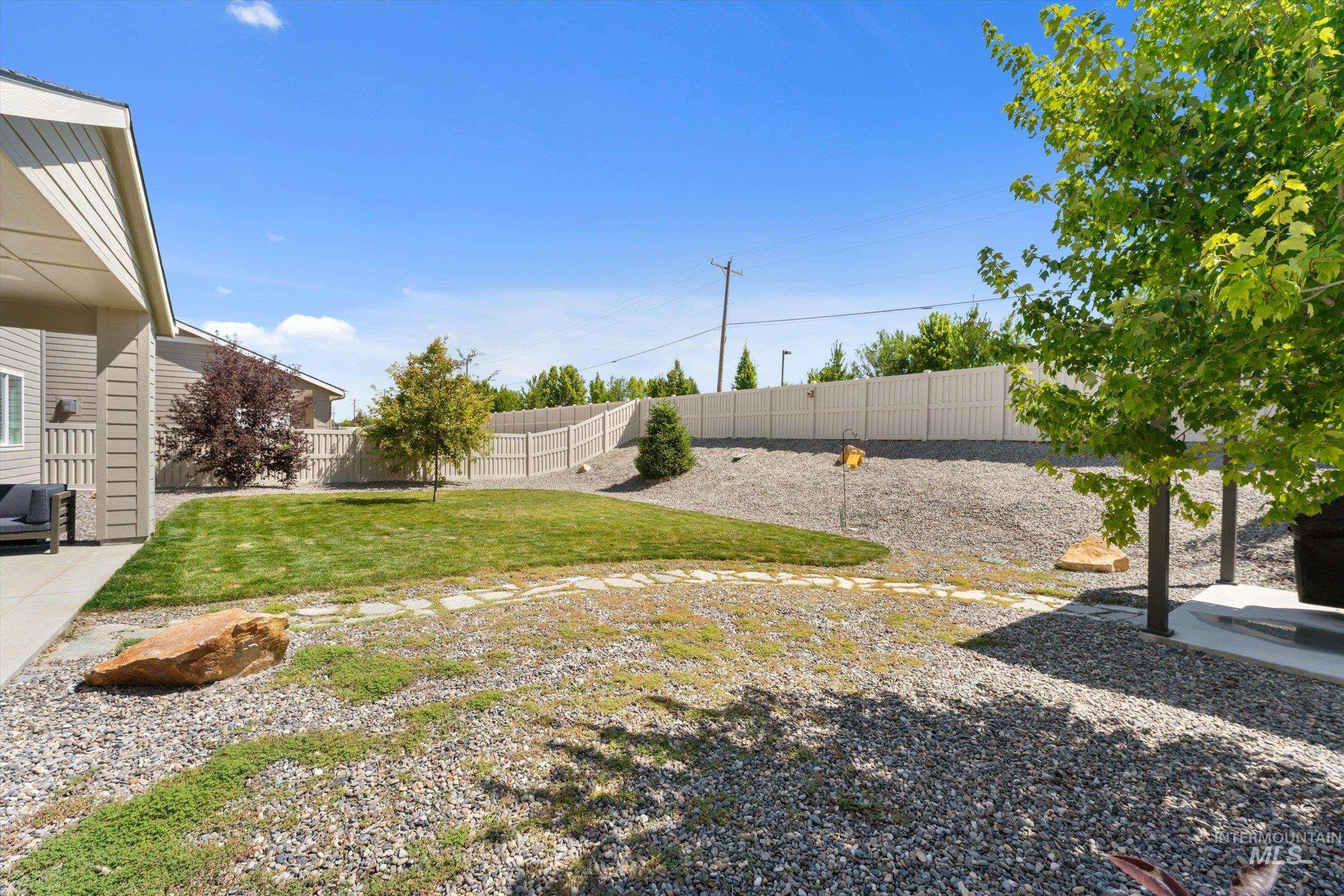 2172 Savoy Court Middleton, ID 83644 - Photo 30 of 46 Expansive backyard featuring a manicured lawn, established trees, and a stone pathway