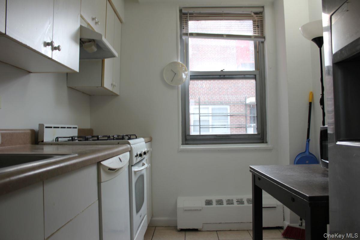 61-25 97th Street, Unit 15J Queens, NY 11374 - Photo 12 of 17 a kitchen with stainless steel appliances a sink a stove and a window