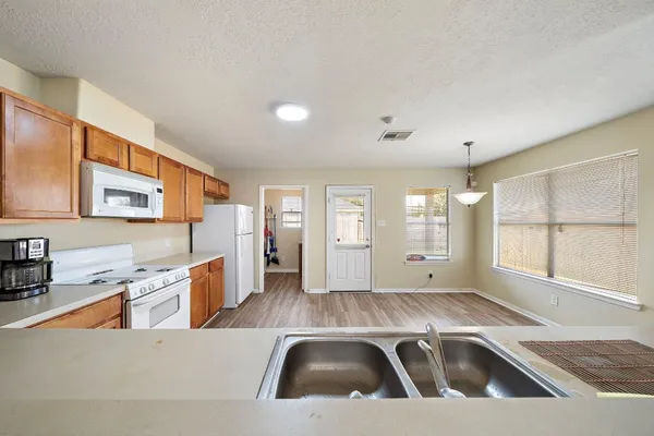 a view of a kitchen with a sink dishwasher and wooden cabinets