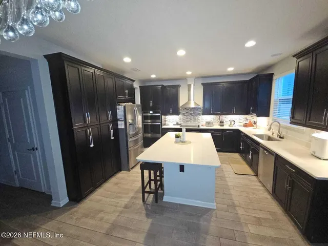 a kitchen with stainless steel appliances kitchen island granite countertop a refrigerator a sink a stove a dining table and chairs