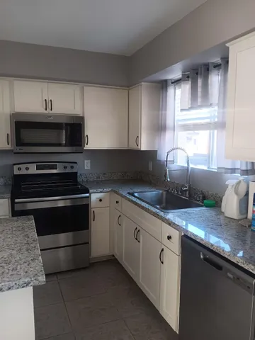 a kitchen with granite countertop a stove and cabinets