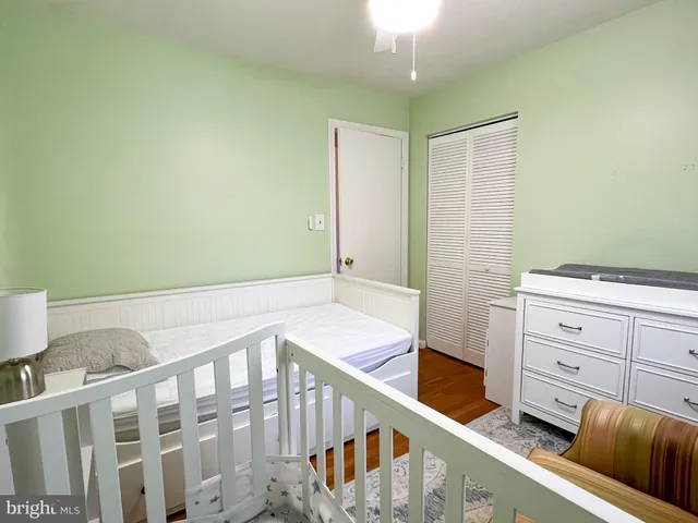 a view of a white house with a big yard and potted plants and large trees