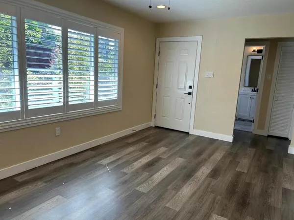 a view of an empty room with wooden floor and a window