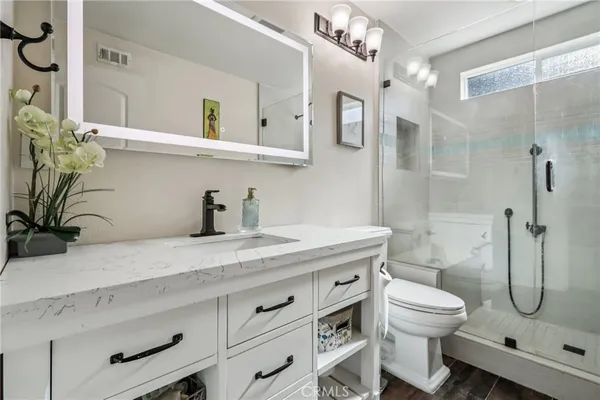 a bathroom with a granite countertop sink a toilet and shower