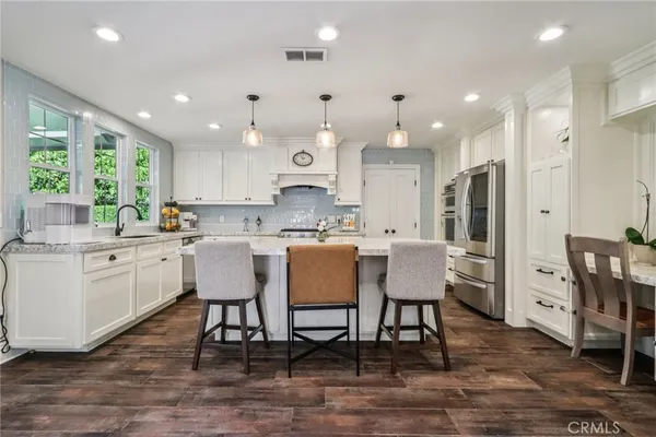 a kitchen with a dining table chairs wooden floor cabinets and a window