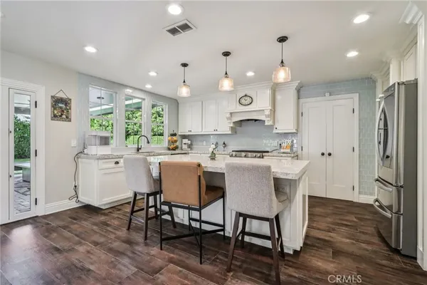 a kitchen with stainless steel appliances kitchen island granite countertop a table chairs and a refrigerator