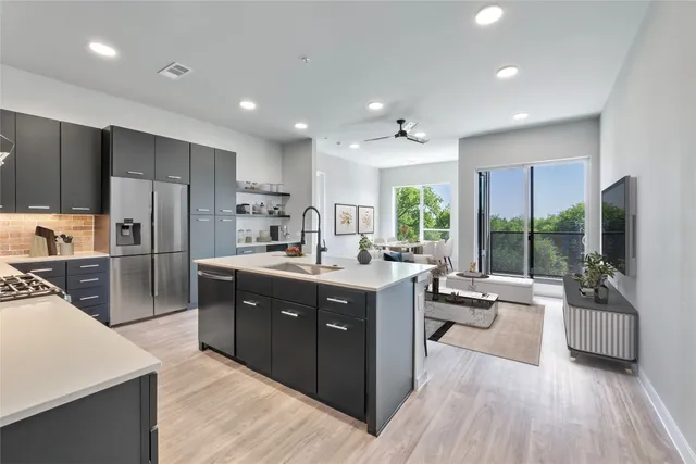 a large kitchen with kitchen island a large counter top space a sink stainless steel appliances and windows
