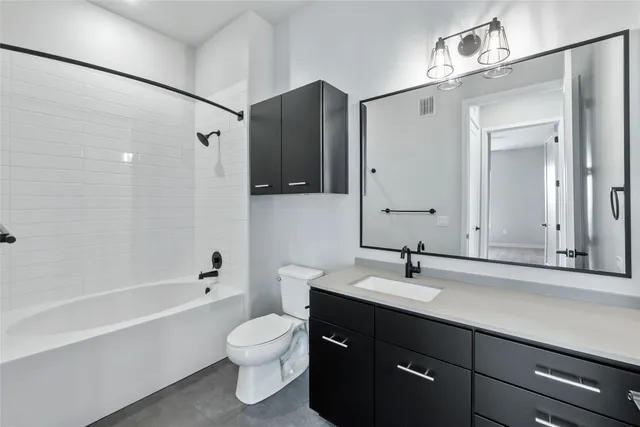 a bathroom with a bathtub shower sink vanity and toilet