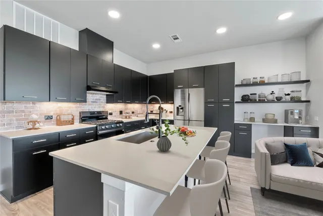 a kitchen with stainless steel appliances a dining table chairs refrigerator and microwave