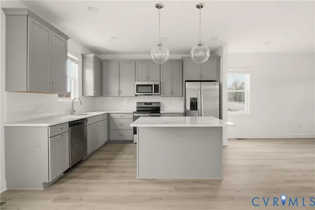 a kitchen with kitchen island granite countertop a sink a counter space stainless steel appliances and cabinets