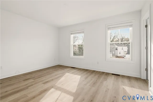 an empty room with wooden floor and windows