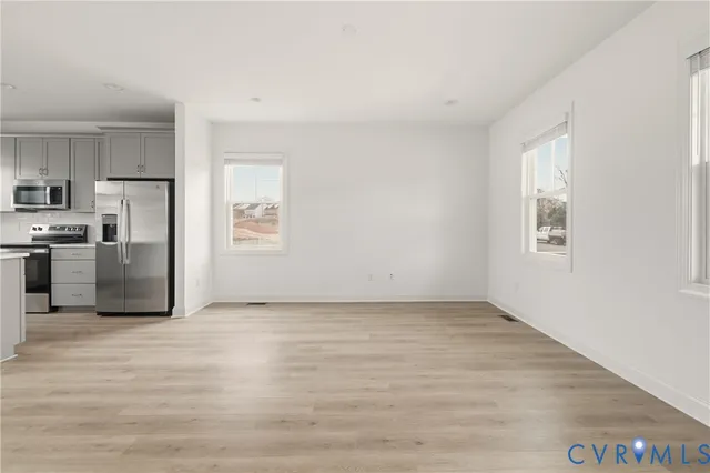a view of kitchen with stainless steel appliances wooden floor and window