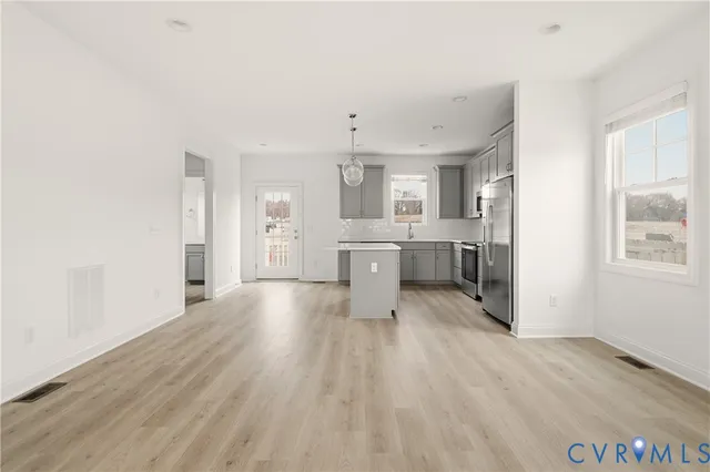 a living room with stainless steel appliances kitchen island hardwood floor and a sink