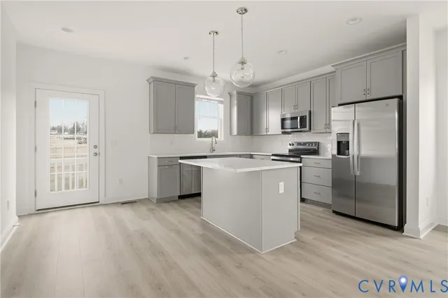 a kitchen with stainless steel appliances a refrigerator a sink dishwasher a stove and white cabinets with wooden floor