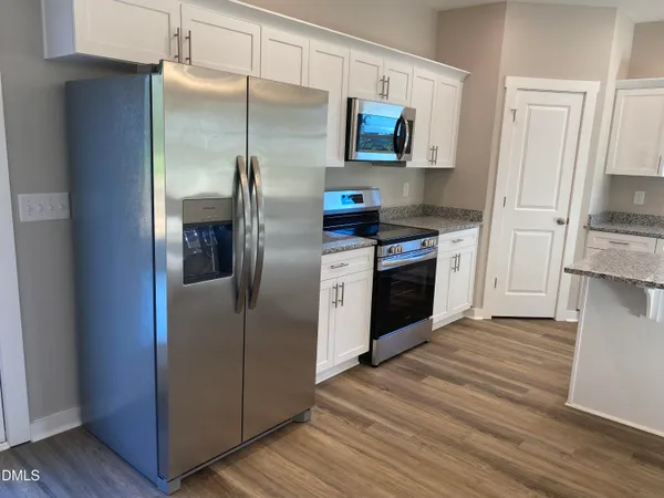a kitchen with stainless steel appliances kitchen island granite countertop wooden floors and view living room