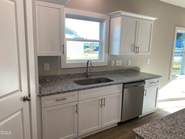 a kitchen with kitchen island granite countertop a sink a counter top space stainless steel appliances and a window