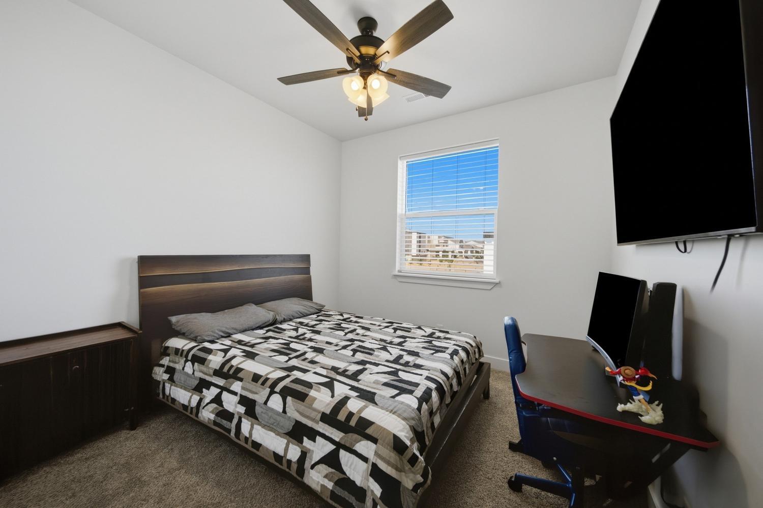 6144 Red Sand Lane St. George, UT 84790 - Photo 12 of 19 Versatile and on-trend, this bedroom pairs a dark wood platform bed with bold graphic bedding for a modern, gender-neutral aesthetic. A built-in desk nook and mounted television make it equally suited to guest use or a home office, while the picture window frames neighborhood views.
