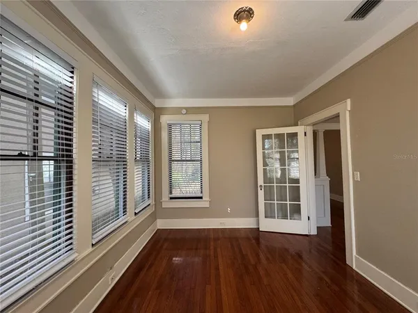 a view of an empty room with wooden floor and a window