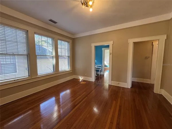a view of an empty room with wooden floor and a window