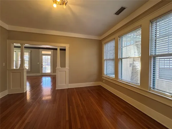 a view of an empty room with wooden floor and a window