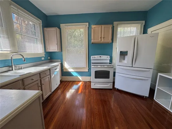 a kitchen with stainless steel appliances a refrigerator a sink and wooden floors